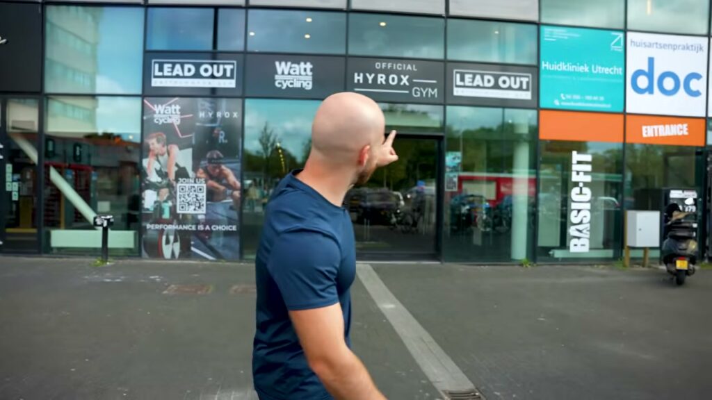Tom van Sportpoeder wijst naar het bord Official HYROX gym van Lead Out in Utrecht